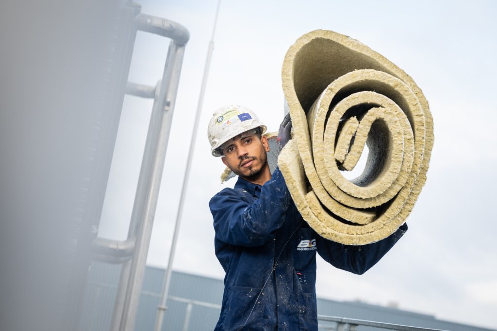 Arbeider draagt isolatiemateriaal op bouwterrein