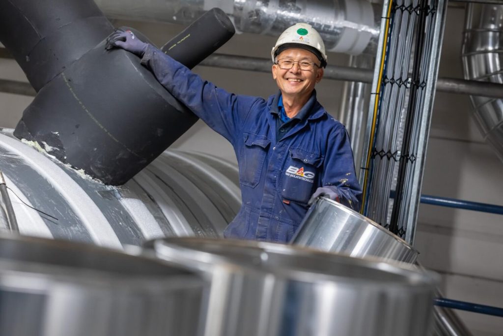 Lachende fabrieksmedewerker in overall en helm.